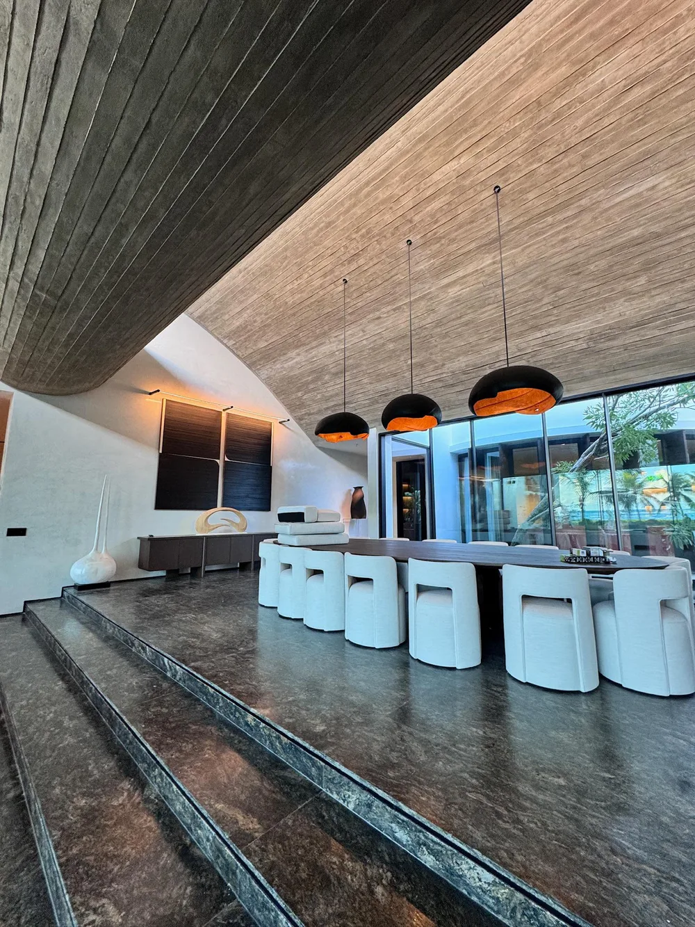 Dining room under a curved wood ceiling with pendant lighting